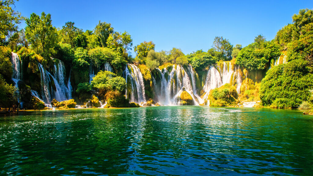 Stunning Kravica Waterfalls in Bosnia and Herzegovina Spectacular cascading waterfalls surrounded by lush greenery flowing into a vibrant blue pool at Kravica Waterfalls, Bosnia and Herzegovina.