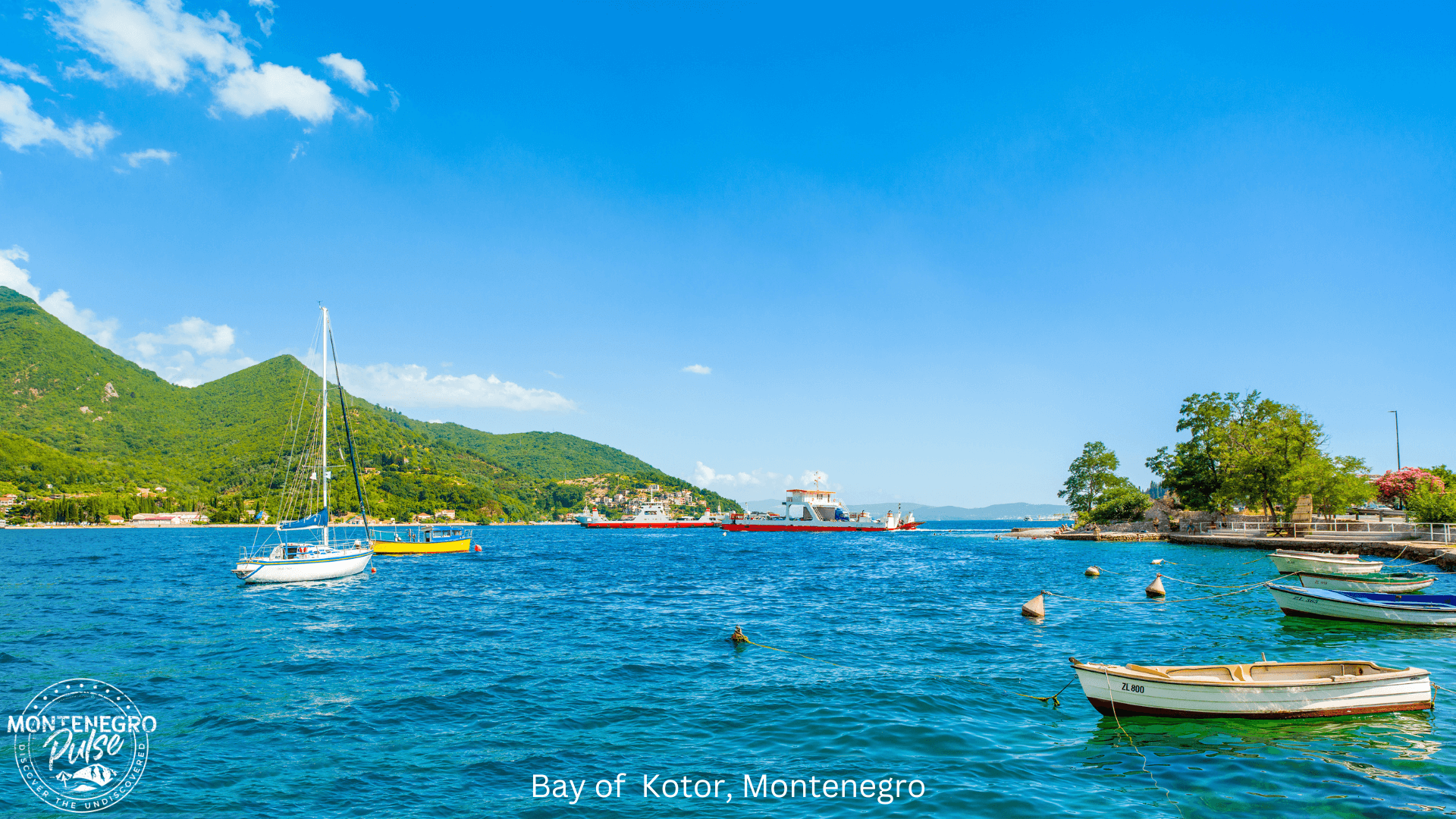 Scenic view of the Bay of Kotor, Montenegro, with boats floating on clear blue waters and green mountains in the background.