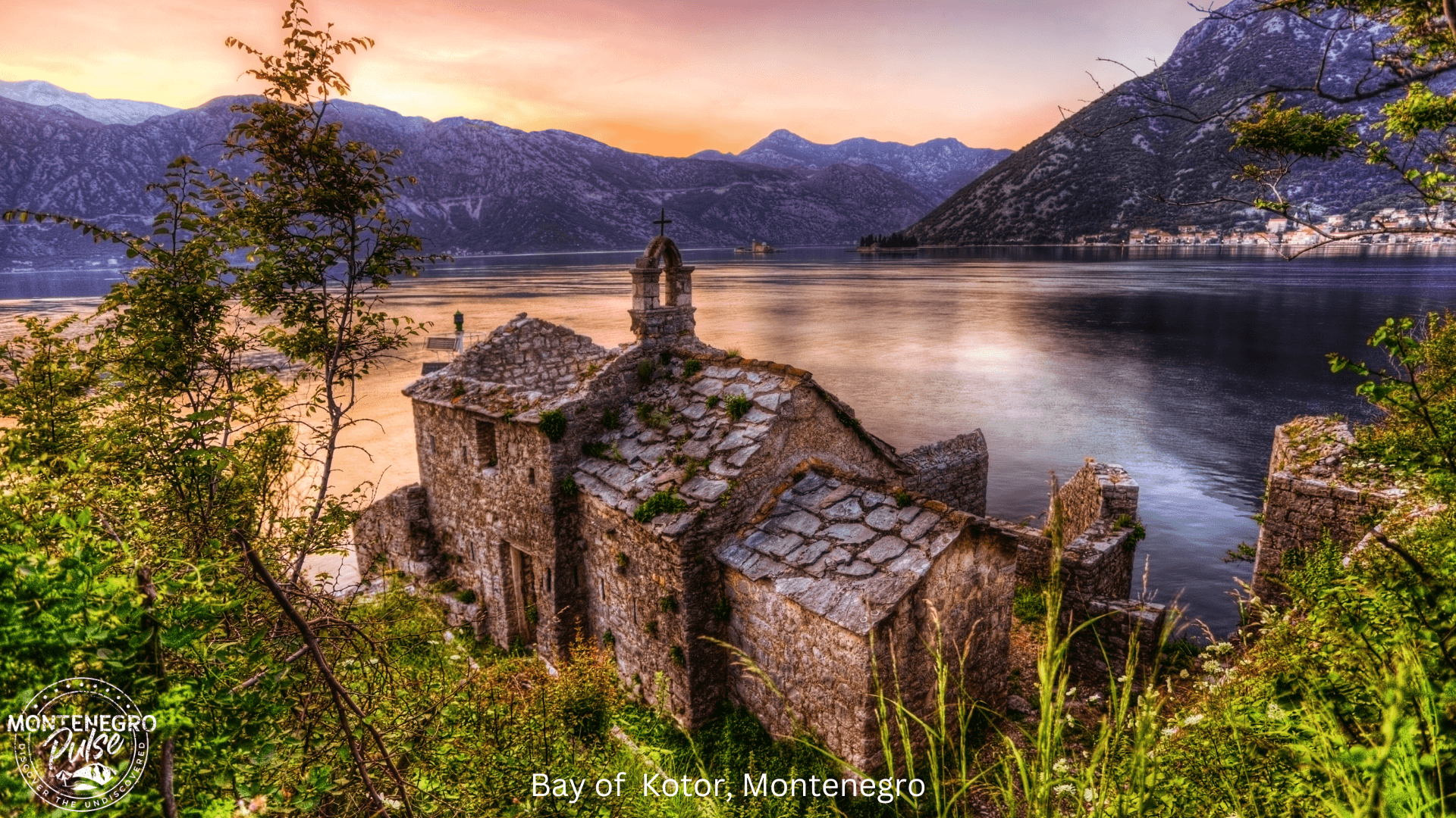 Ruins of a stone church with a bell tower overlooking the Bay of Kotor at sunset, Montenegro.