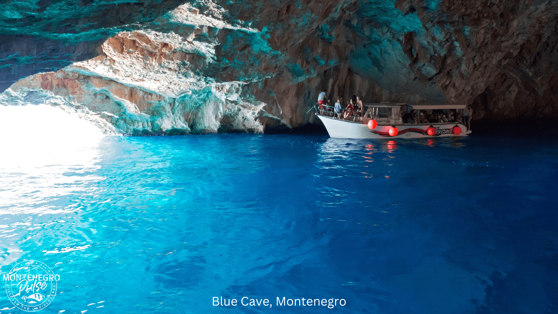 A boat entering the Blue Cave, with crystal blue waters and dramatic cliffs in Montenegro.