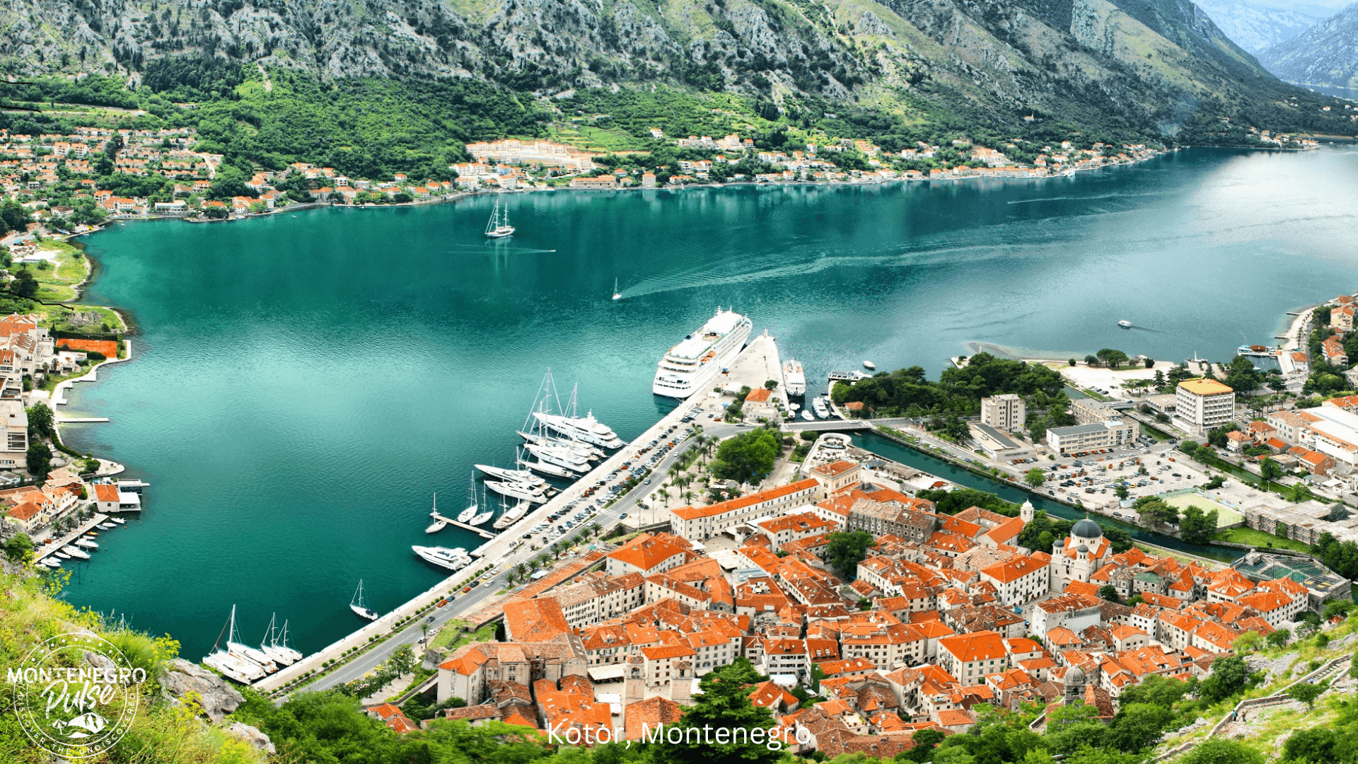 Aerial view of Kotor with its red-roofed buildings, harbor, and surrounding mountains in Montenegro.