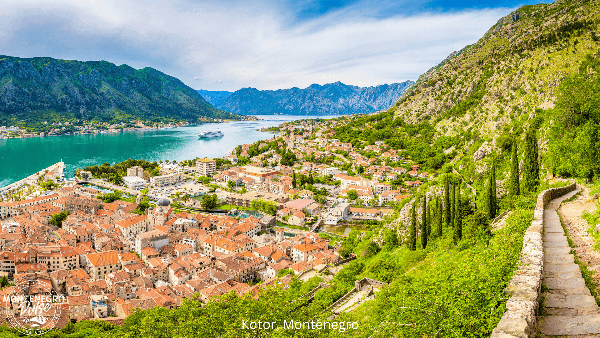 Panoramic view of Kotor's Old Town, bay, and lush mountains from the fortress path, Montenegro.