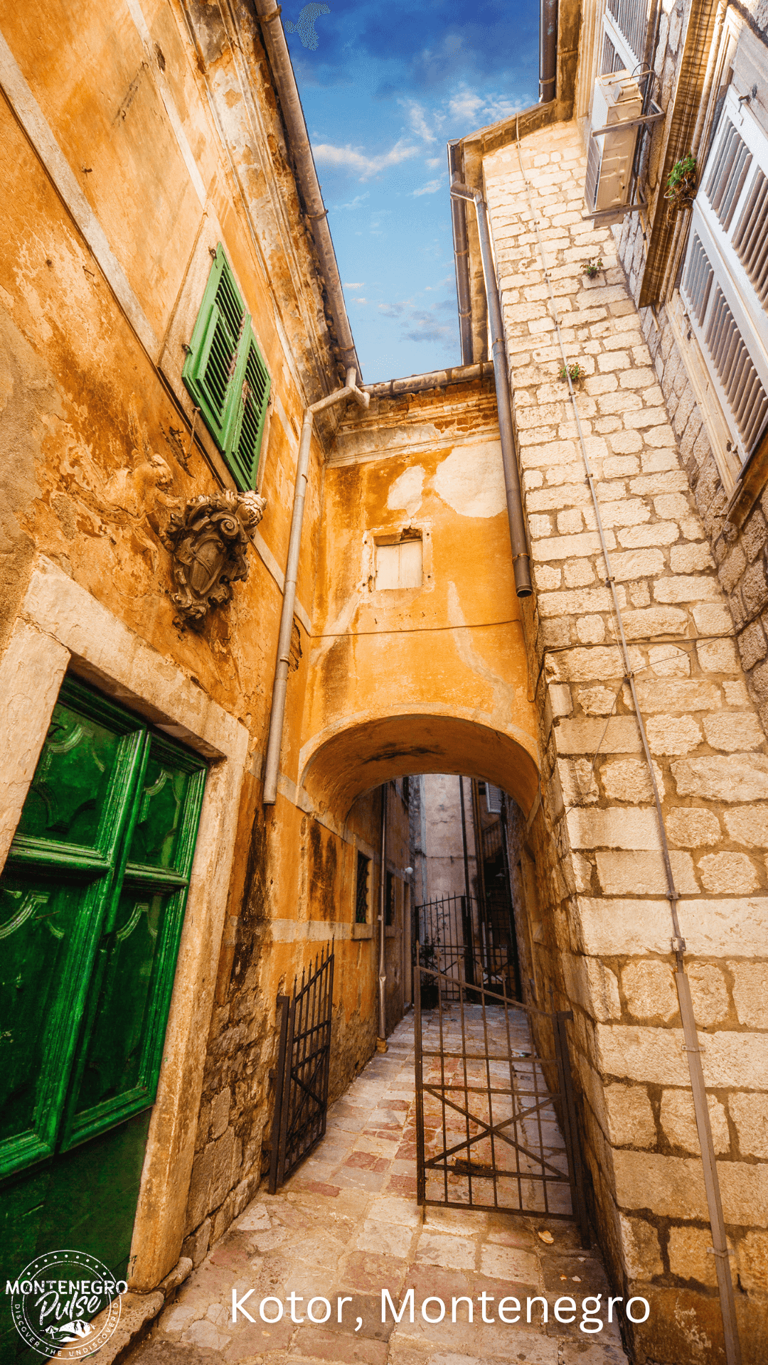 Narrow street in the old town of Kotor, Montenegro, with historical buildings and green shutters.